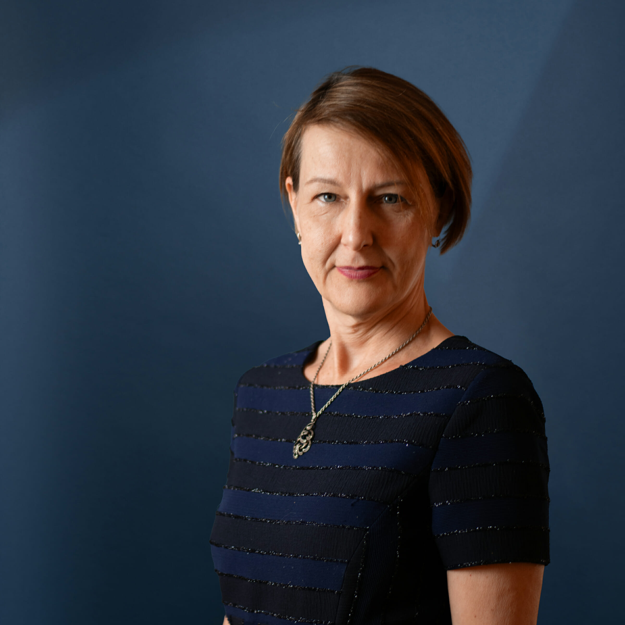 Headshot of Zsuzsanna Gaspar with blue background