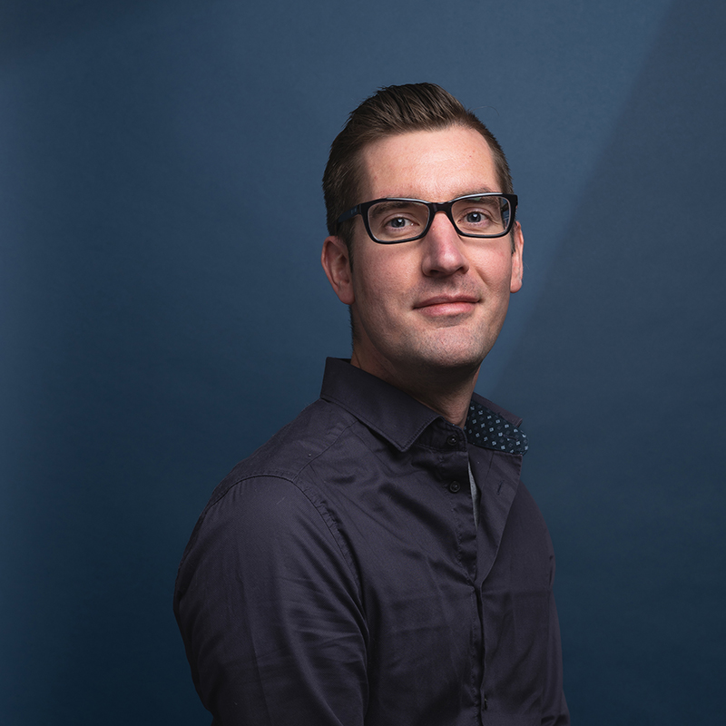 Headshot of Justin Dufresne with blue background