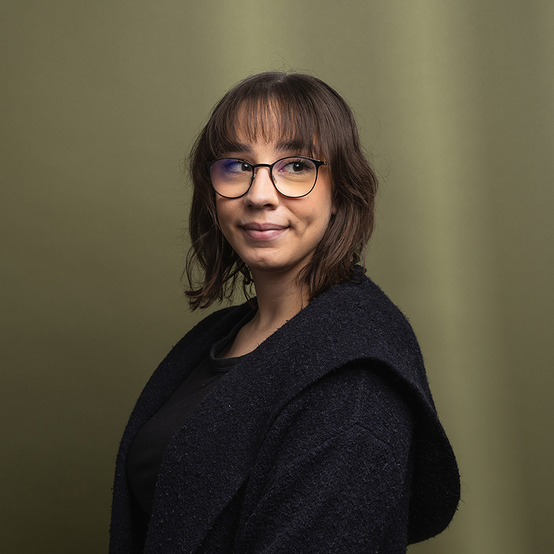 Headshot of Alicia Does with dark green background