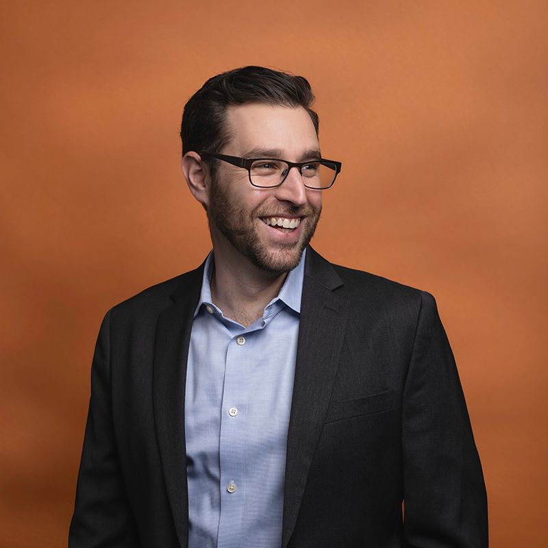 Headshot of David Charney with orange background