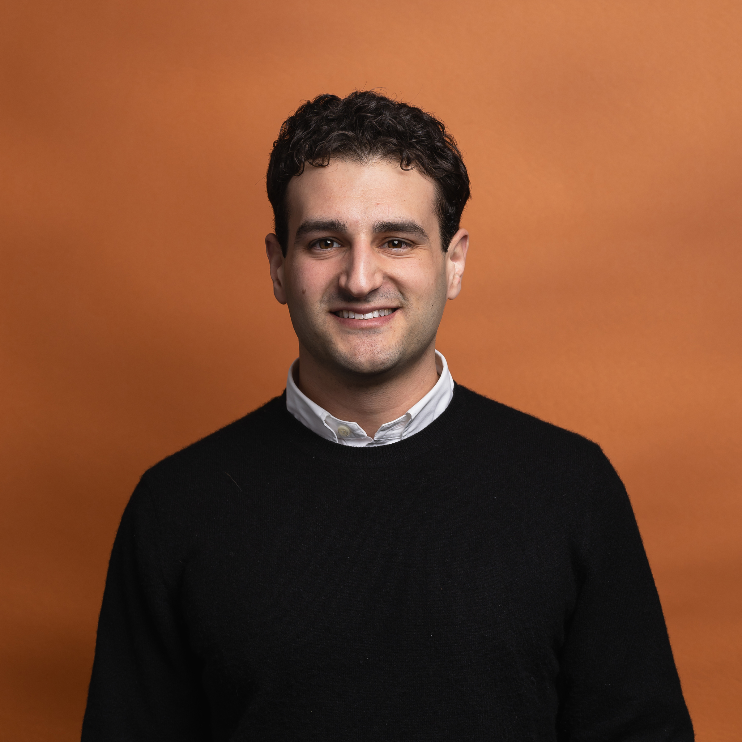 Headshot of James Charves with orange background