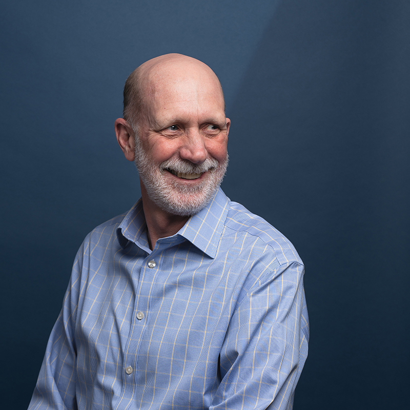 Headshot of John Benson with blue background