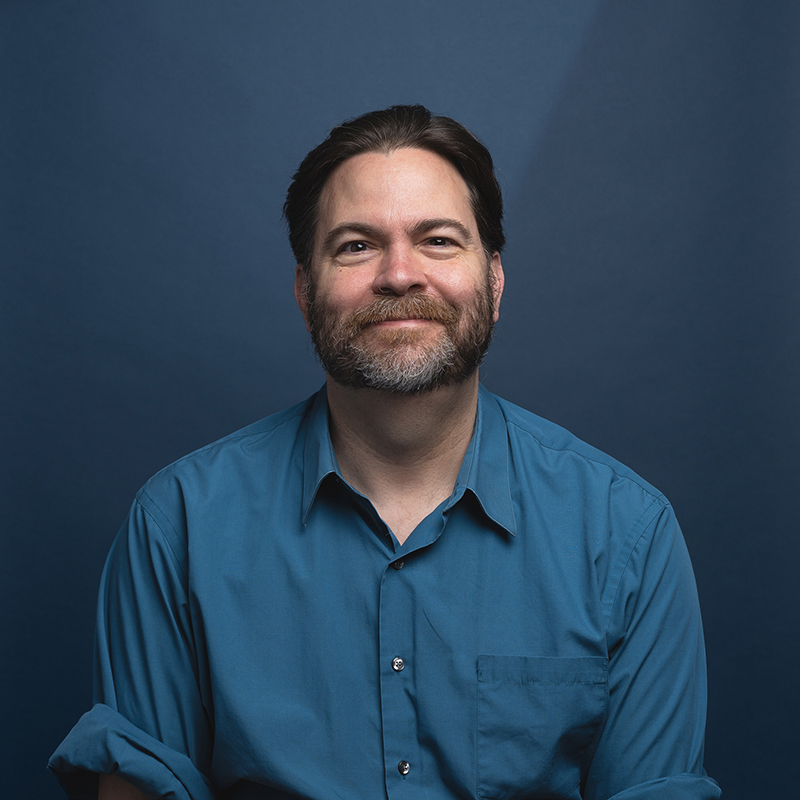 Headshot of Michael Feely with blue background
